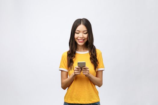 Attractive Asian teenage girl looking at her mobile phone screen with joyful face, on white background for copy space