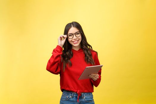 Picture of happy teenage girl with tablet pc computer isolate on yellow background.