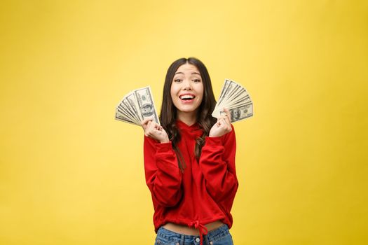 Closeup of young beautiful woman with us dollar money in hand over yellow background, with copy space.