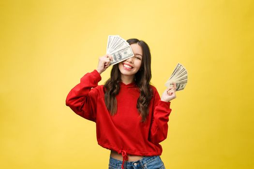 Closeup of young beautiful woman with us dollar money in hand over yellow background, with copy space.