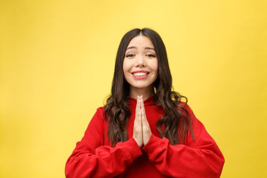 Getting concentration from space. Portrait of good-looking young european female, holding hands in pray, focused on wishing over yellow background.