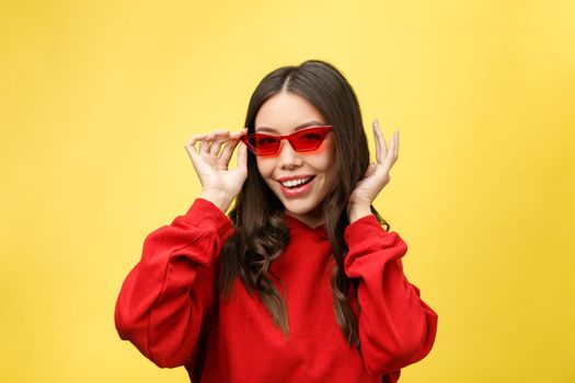 Pretty happy woman in red sunglasses over colorful background.