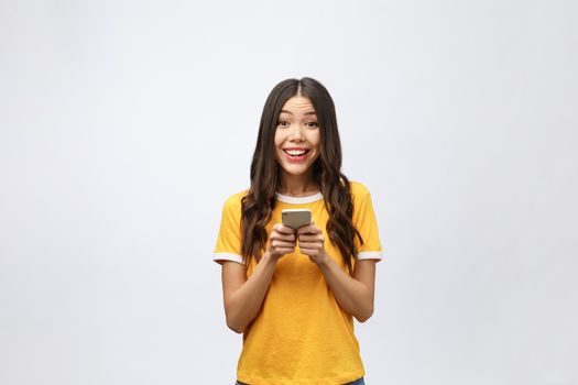 Attractive Asian teenage girl looking at her mobile phone screen with joyful face, on white background for copy space