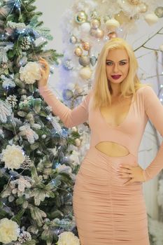 Charming blonde woman in beige sexy dress. Christmas and New Year photo.