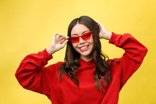 Pretty happy woman in red sunglasses over colorful background.