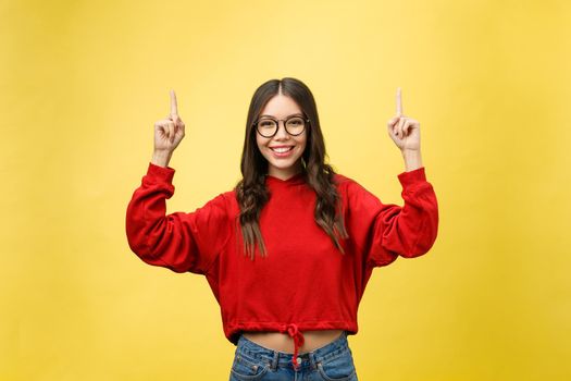 Young beautiful asian woman pointing to copyspace, isolated on yellow background.