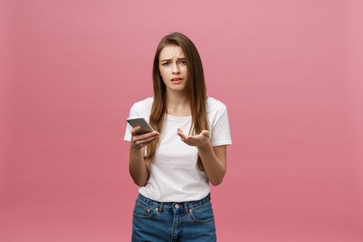 Serious young woman talking on phone isolated on pink. Copy space and fashion. Mock up