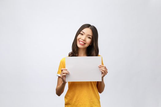 advertising banner sign - woman excited pointing looking down on empty blank billboard paper sign board. Young business woman isolated on white background.