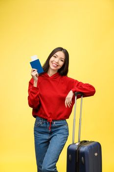 Woman travel. Young beautiful asian woman traveler with suitcase and passport on yellow background.