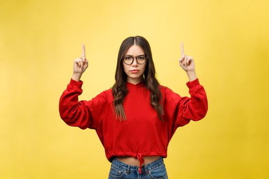 Young beautiful asian woman pointing to copyspace, isolated on yellow background.