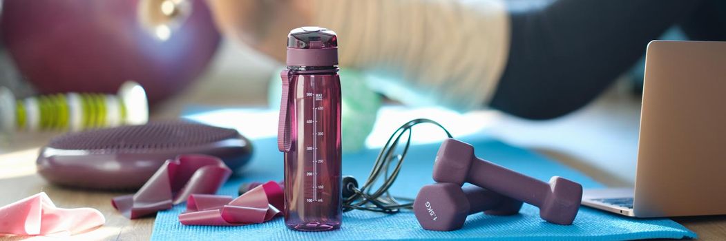 Sports equipment and accessories on the floor for fitness at home. Woman doing abdominal exercises, rest from work