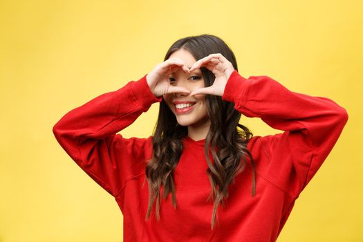 portrait smiling young woman making heart sign with hands