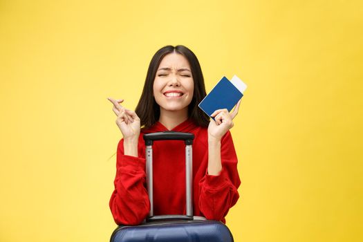 Woman travel. Young beautiful asian woman traveler with passport and suitcase on yellow background.