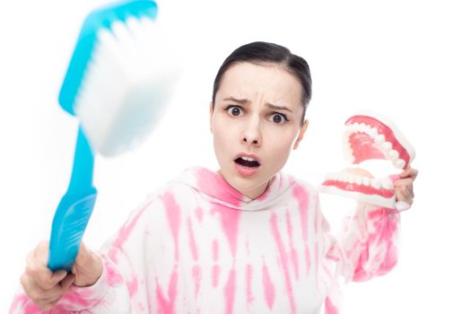excitedly surprised woman with a huge toothbrush and tooth jaw in her hands, on a white background. High quality photo