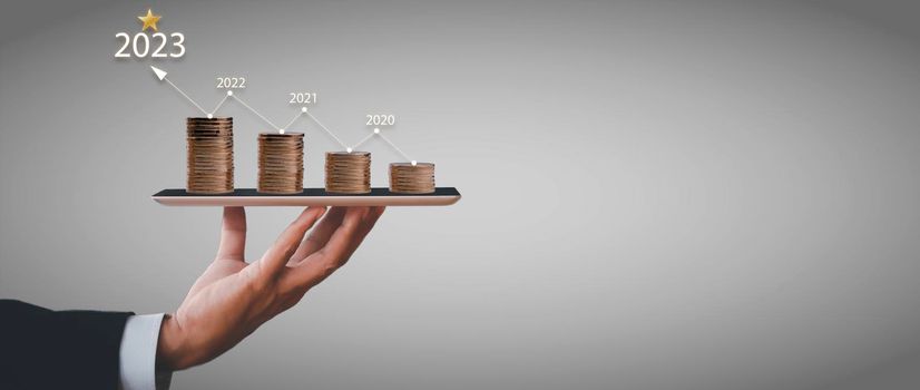 Businessman holding tablet with step coin grows and line arrow with number of year. The idea of maximizing the profit from the business investment.
