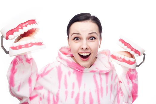 happy woman in pink sweatshirt holding dental mock-ups of the jaw in her hands. High quality photo