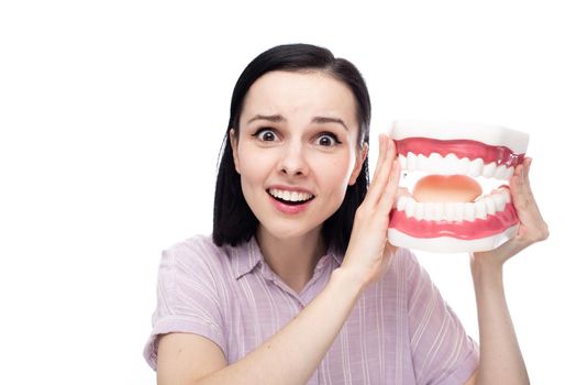 surprised woman in a purple shirt holds a huge jaw mockup in her hand, white background. High quality photo