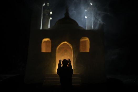 Silhouette of mosque building on toned foggy background. Ramadan Kareem background. Realistic mosque miniature with prayer silhouette. Selective focus