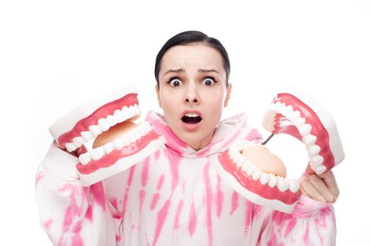 frightened woman in a pink sweatshirt holding dental jaw models in her hands. High quality photo