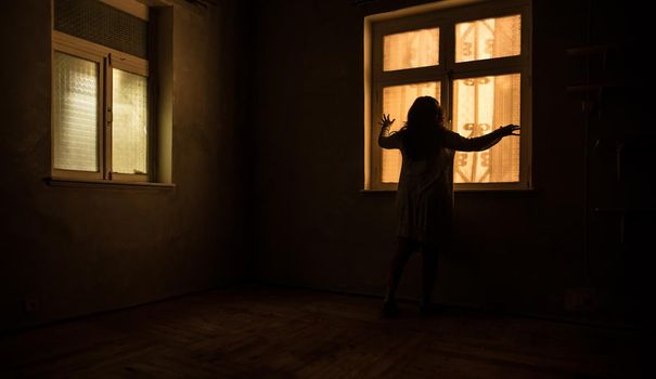 Horror silhouette inside abandoned creepy room with window at night. Horror scene. Halloween concept.