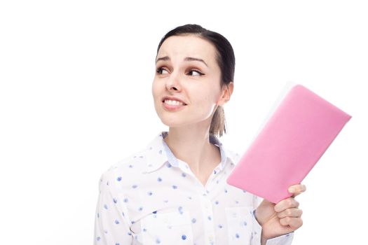 cute woman in a white shirt holding a pink notebook in her hands, white studio background. High quality photo