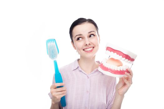 happy woman in a purple shirt holding a huge toothbrush in her hand a huge jaw mockup. High quality photo