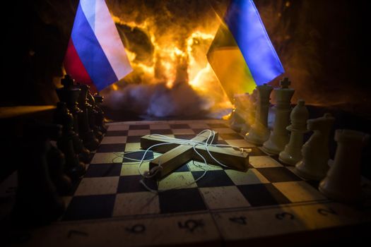 Concept of war or manipulation with global politics. War between Russia and Ukraine, conceptual image of war using chess board and national flags on the background of explosion.