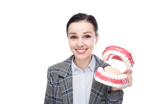 smiling woman in an office suit holds a dental model of the jaw in her hands, white background. High quality photo