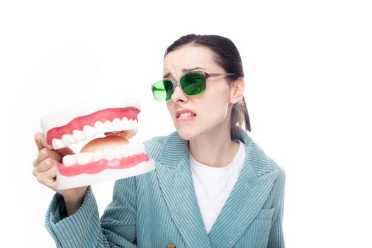 woman in green glasses lovingly looks at the dental jaw, white background. High quality photo