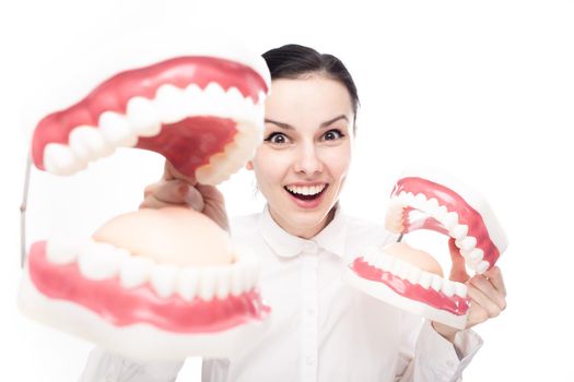 smiling female employee of a dental clinic in a white shirt holding giant jaws in her hands. High quality photo