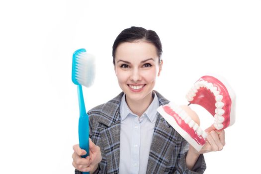 happy woman in office suit holding big toothbrush and big jaw mockup with teeth, white background. High quality photo