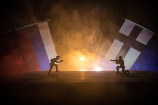 Flags of Finland and Russia on dark background. Conceptual image of war between Russia and Finland using toy soldiers and national flags . Selective focus