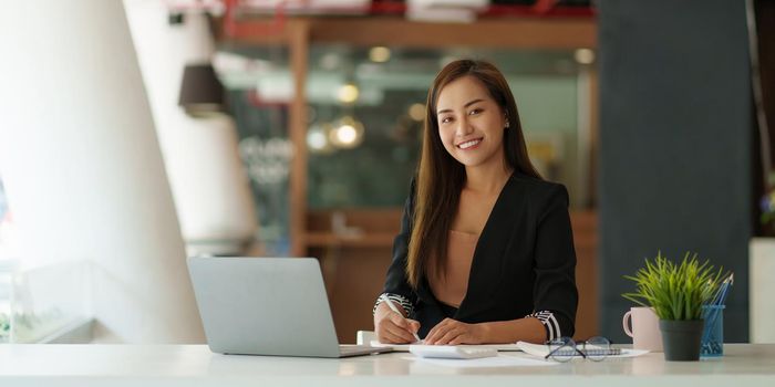 A portrait of Asian happy Businesswoman smiling and working at office