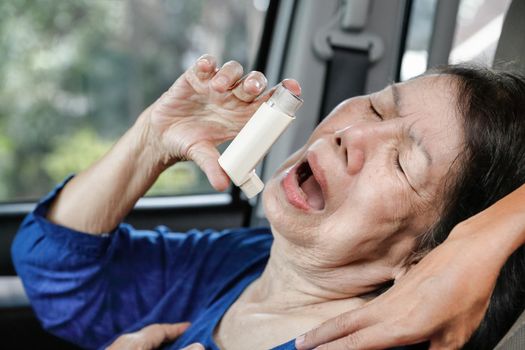 Elderly woman choking and holding an asthma spray inside car on the way