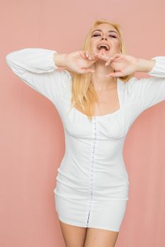 Spring fashion photo of blonde woman posing over pink background. Wearing white vintage dress with long sleeves