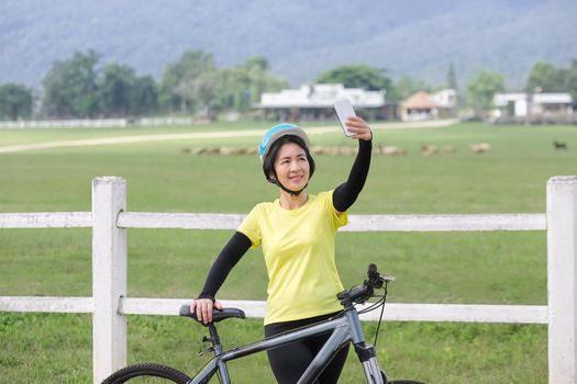 Middle aged women take self photo with phone on her bicycle