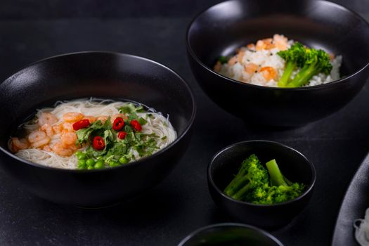 Various dishes of Asian cuisine with different types noodles and rice with shrimp, vegetables and black sesame