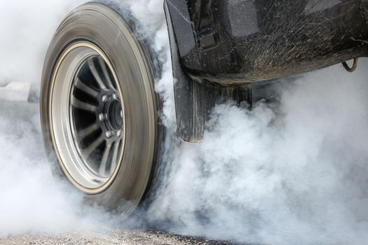 Drag racing car burns rubber off its tires in preparation for the race