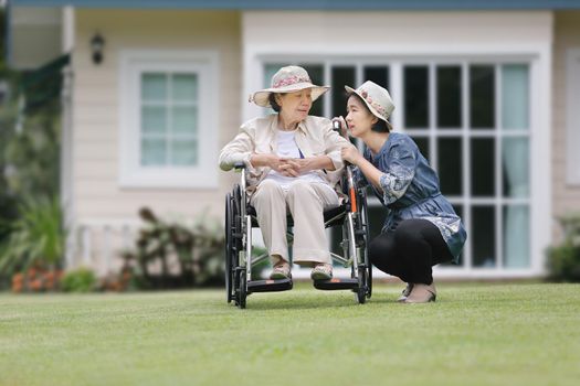 Elderly woman relax on wheelchair in backyard with daughter