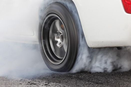 Drag racing car burns rubber off its tires in preparation for the race