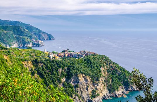 Corniglia traditional typical Italian village with colorful buildings on rock cliff and Manarola, Genoa Gulf, Ligurian Sea, blue sky background, National park Cinque Terre, La Spezia, Liguria, Italy