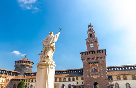 Monument of Czech saint John Nepomuk with cross, Tower Torrione del Carmine, La torre del Filarete and brick walls of old medieval Sforza Castle Castello Sforzesco courtyard, Milan, Lombardy, Italy