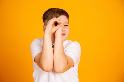 The boy looks like through binoculars. Hands folded into a straw. Boy is watching looking through hands
