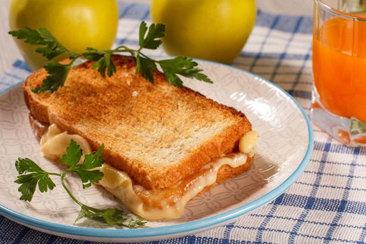 Good and delicious food and beverages for breakfast. Toast with butter and cheese on white plate, two apples, glass of orange juice on kitchen napkin