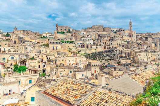 Sassi di Matera old ancient town, aerial panoramic view of historical centre Sasso Caveoso with rock cave houses, blue sky and white clouds, UNESCO World Heritage, Basilicata, Southern Italy