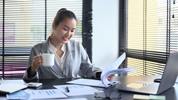 Smiling female accountant advisor checking financial reports at her workplace.