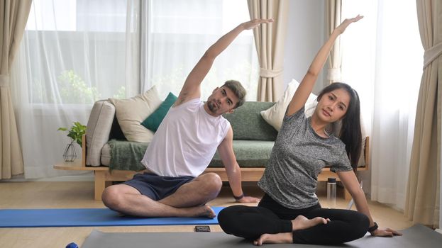 Young couple in sports clothes is meditating ,practicing yoga at home. Sport at home, workout, fitness and exercises.