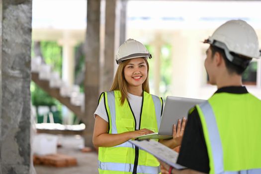 Shot of team of specialists wearing hardhat talking and walk in construction site. Building construction collaboration concept.