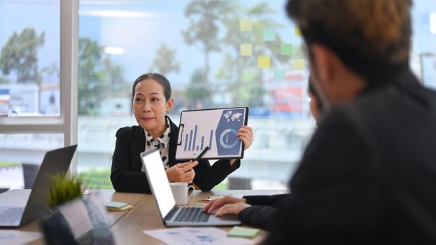 Focused middle aged executive business leader presenting business seminar in boardroom.