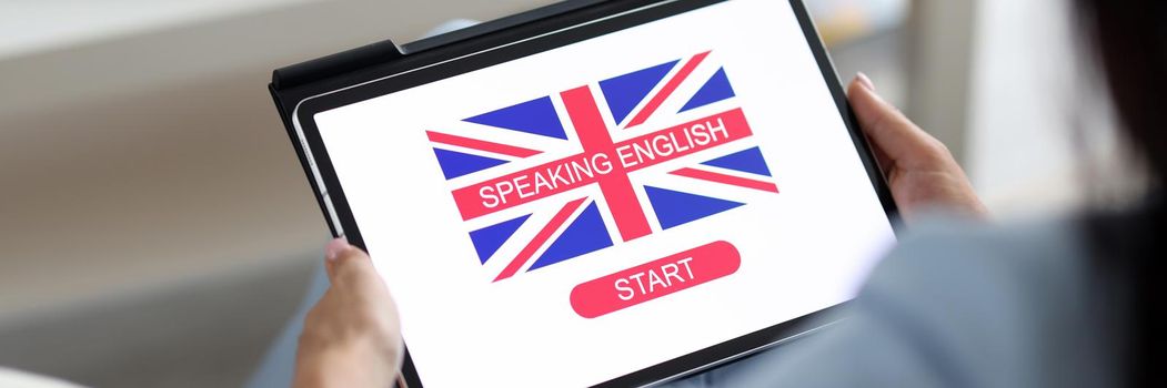 A man holds a tablet with a program for learning English, close-up. Flag of Britain on the screen of the device, online course